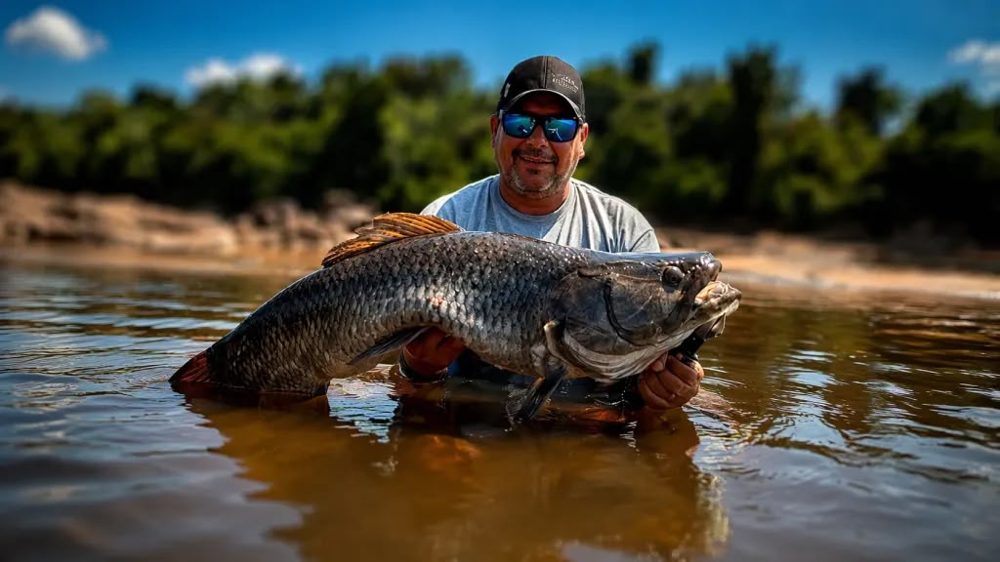 Rodrygo holding a large wolf fish (trairão) in a river